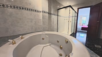 A modern bathroom with a freestanding bathtub, a glass-enclosed shower, and a marble floor.