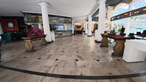 A lobby with marble flooring, white columns, and a reception desk.