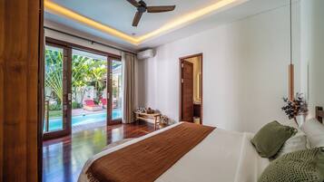A bedroom with a large bed, a ceiling fan, and a view of a pool and outdoor seating area.