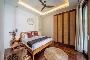 A modern bedroom with a wooden bed, a ceiling fan, a wall-mounted light, and a large wardrobe.