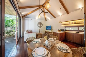 Een moderne keuken met houten balken, een eettafel voor vier personen en een aan de muur bevestigde televisie.