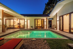 Een modern huis met een zwembad, een eethoek en een woonkamer.