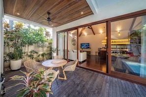 A spacious patio with a wooden deck, a round table, and wicker chairs.