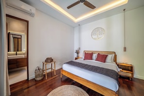 A bedroom with a bed, bedside tables, a ceiling fan, and a wall-mounted air conditioner.