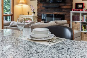 A dining area with a granite table, white plates, a clear glass, and a candle holder.