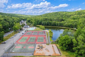 A sports complex with multiple tennis courts, a swimming pool, and a playground.