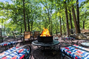An outdoor seating area with a fire pit surrounded by chairs and tables.