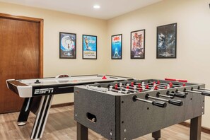 A room with a foosball table and four movie posters on the wall.