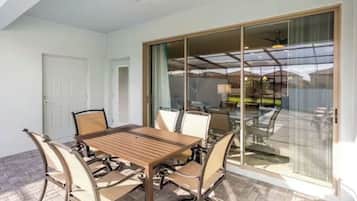 A dining area with a wooden table and chairs, a sliding glass door leading to an outdoor patio, and a ceiling fan.