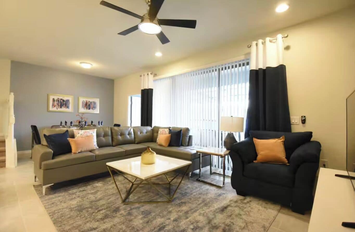 A living room with a sofa, coffee table, and a ceiling fan.