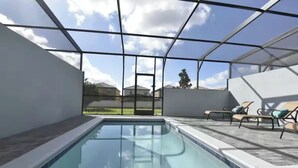Ein modernes Hallenbad mit großen Glaswänden, einer gefliesten Liegefläche und Liegestühlen.