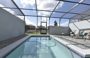 A modern indoor swimming pool with clear glass walls, a tiled deck, and lounge chairs. - SuperHero's 5-bedroom home in marvelous Orlando with Pool (Kissimmee)