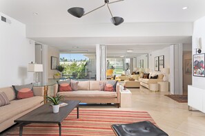 A spacious living area with a sofa, coffee table, and a view of the outdoors. - Seven Lakes Golf and Country Club 2 bedroom plus Den bungalow (Palm Springs)