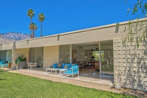 A modern house with a patio area featuring outdoor furniture, a large sliding glass door, and a view of a mountain range. - Seven Lakes Golf and Country Club 2 bedroom plus Den bungalow (Palm Springs)
