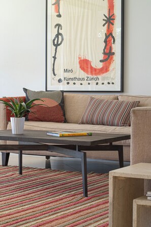 A living room with a sofa, a coffee table, a potted plant, and a colorful striped rug. - Seven Lakes Golf and Country Club 2 bedroom plus Den bungalow (Palm Springs)