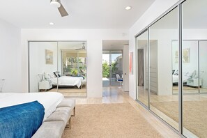 A modern bedroom with a bed, a bench, and a large sliding glass door leading to a balcony. - Seven Lakes Golf and Country Club 2 bedroom plus Den bungalow (Palm Springs)