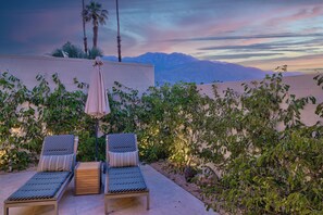A terrace with two lounge chairs, a table, and an umbrella. - Seven Lakes Golf and Country Club 2 bedroom plus Den bungalow (Palm Springs)