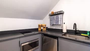 Eine moderne Küche mit Backofen, Geschirrspüler, Spüle mit schwarzem Wasserhahn und einer Weinflasche auf der Arbeitsfläche.