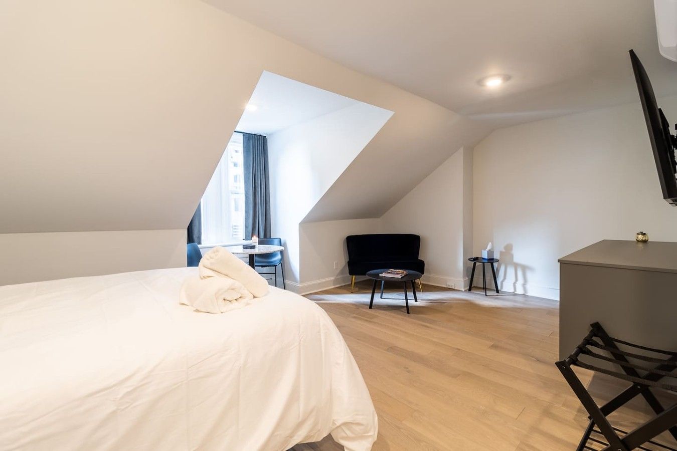 A bedroom with a bed, a desk, a chair, and a small table.