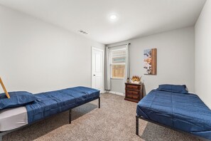 Un dormitorio con dos camas individuales, un aparador, una puerta y una ventana con persianas.