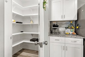 Une cuisine moderne avec des meubles blancs, un plan de travail en granit et une machine à café.