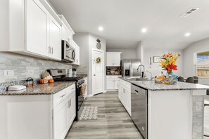Una cocina moderna con armarios blancos, electrodomésticos de acero inoxidable y encimera de granito.