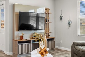 Una sala de estar moderna con un televisor de pantalla plana montado en un mueble de madera, un sofá y decoración de pared.