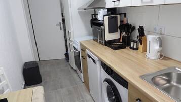 Eine kleine Küche mit Waschmaschine, Kaffeemaschine und Toaster.