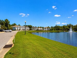 Un quartier résidentiel avec un lac, une fontaine et des maisons en arrière-plan.