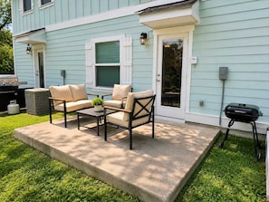 A patio with outdoor furniture, a grill, and a house with light blue siding. - Beach Days and Pool Nights - PCB Sleeps 8 (Panama City Beach)