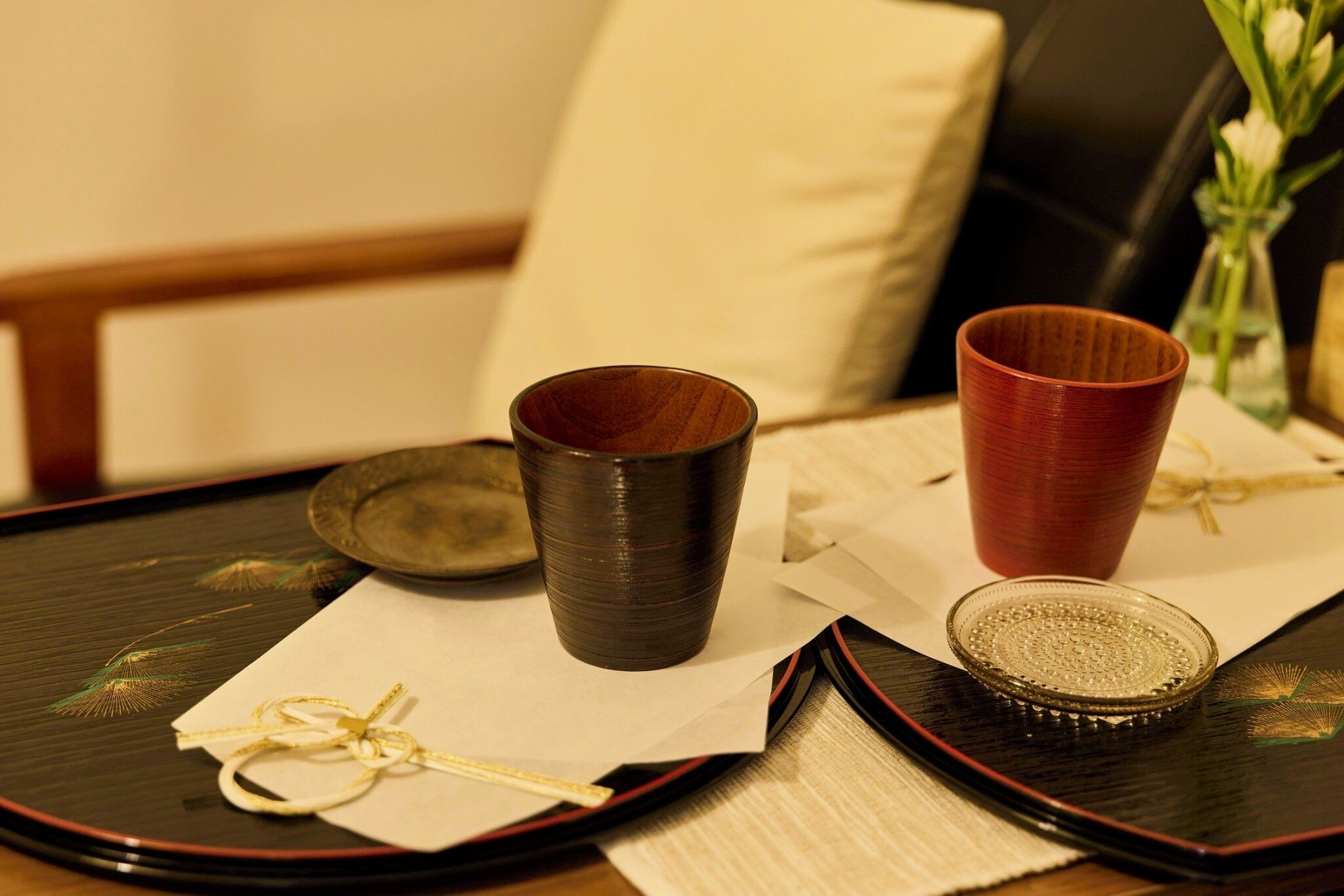 A table with two wooden cups, a glass plate, and a small bowl on a tray.