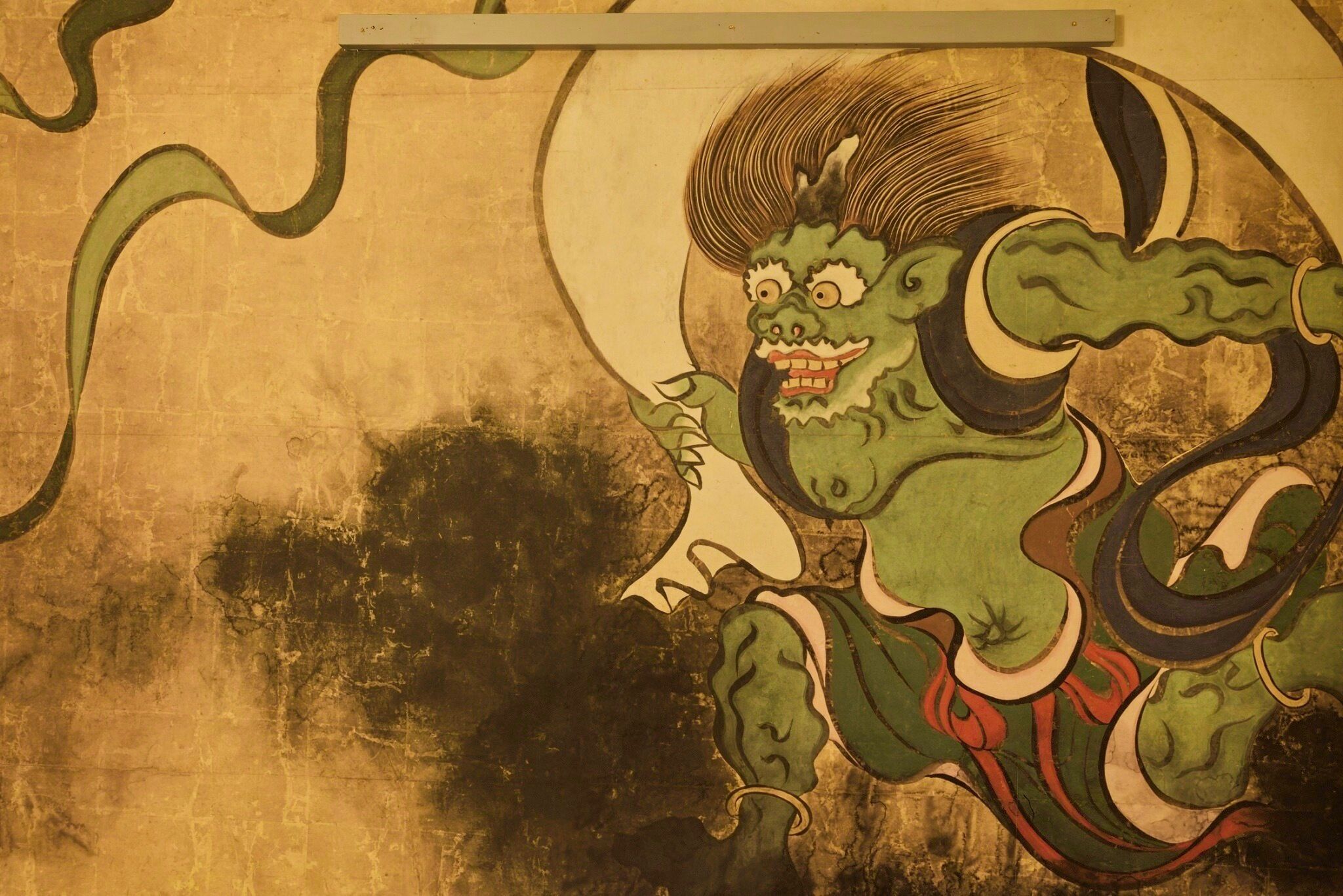 A wall with a traditional mural featuring a green dragon-like figure.