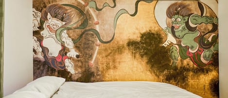 A room with a bed and a large wall mural depicting mythical creatures.