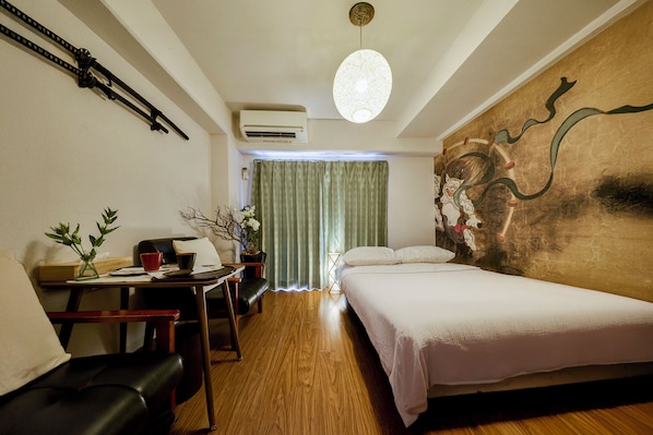 Una habitación de hotel con una cama, un escritorio con una silla, una mesa con un jarrón y un cuadro en la pared.