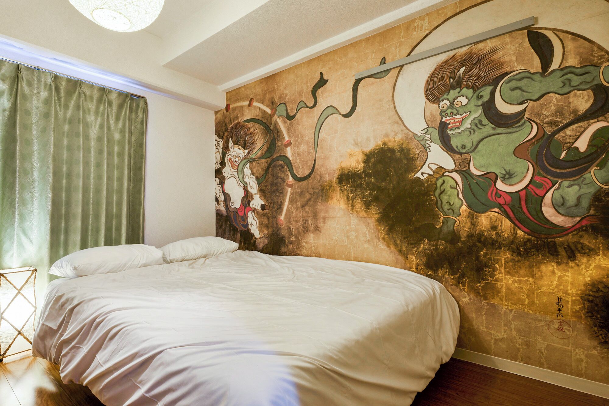 A room with a large bed, a green curtain, and a wall mural.