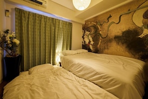 Habitación de hotel con dos camas, un mural grande en la pared y una planta en maceta.