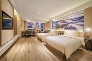 Een hotelkamer met twee bedden, een bureau, een stoel, een televisie en een groot landschap op de muur.
