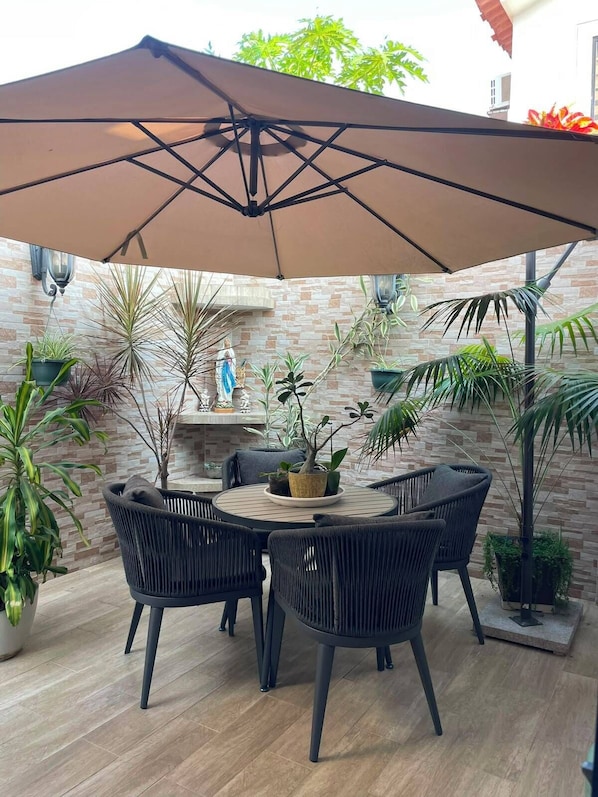 A patio with a round table, four chairs, and a large umbrella.
