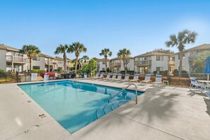A swimming pool with lounge chairs and palm trees, surrounded by multi-story buildings. - Modern Retreat - Pool  - Walk to Beach (Miramar Beach)