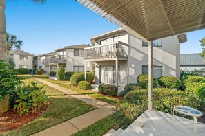 Un edificio residencial con varios balcones, un patio cubierto y jardines bien cuidados.
