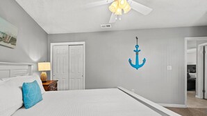 A bedroom with a bed, a ceiling fan, a door, and a wall-mounted anchor decoration. - Modern Retreat - Pool  - Walk to Beach (Miramar Beach)