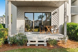 Una casa moderna con un porche cubierto, puerta corrediza de vidrio y una pequeña zona de estar exterior con mesa y sillas.