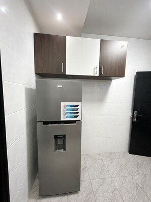 A kitchen with a built-in refrigerator, a water dispenser, and wooden cabinets. - Modern & Comfortable Residence in Angré (Abidjan)