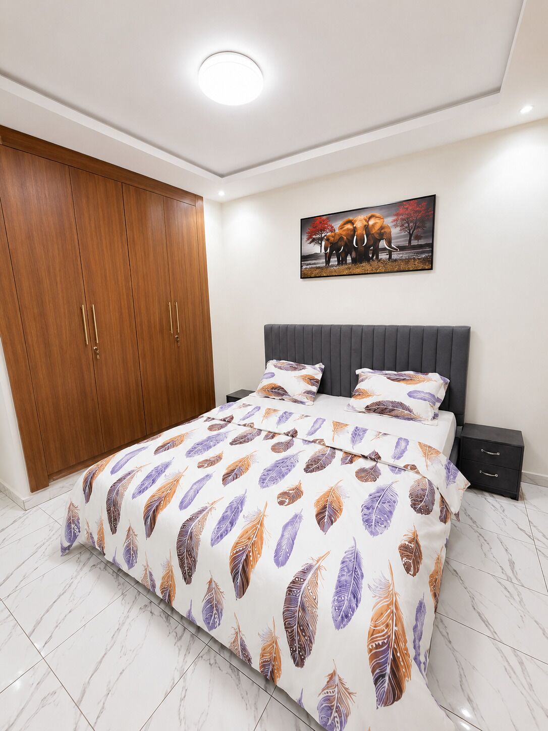 Une chambre à coucher avec un lit, une armoire, une table de chevet et un tableau au mur.