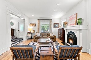 Una sala de estar con chimenea, un sofá, una mesa de centro y alfombras estampadas.
