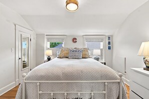 A bedroom with a bed, bedside tables, a lamp, and a window with curtains. - Historic Mapleton Hill Home with Victorian Charm and Modern Amenities (Boulder)