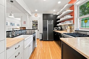 A modern kitchen with a central island, built-in appliances, and a wooden floor. - Historic Mapleton Hill Home with Victorian Charm and Modern Amenities (Boulder)