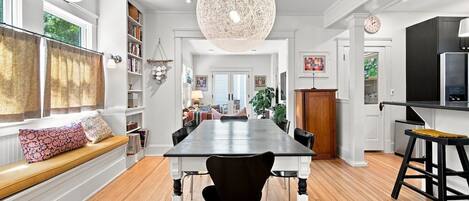 A spacious dining area with a long table, black chairs, and a large woven light fixture.