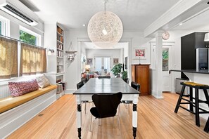 A spacious dining area with a long table, black chairs, and a large woven light fixture. - Historic Mapleton Hill Home with Victorian Charm and Modern Amenities (Boulder)