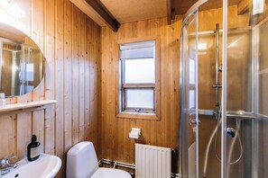 A wooden-paneled bathroom with a shower, a sink, and a window. - Hlíð Cottages (Myvatn)